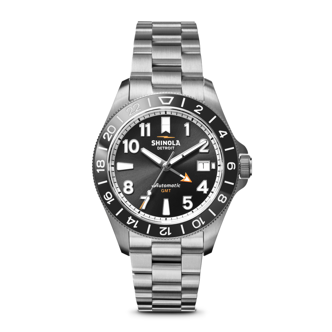 The Shinola Monster GMT Automatic Watch – Black features a stainless steel case and bracelet, black dial, white hour markers, orange GMT hand, and a date window at 3 o'clock, shown against a white background.